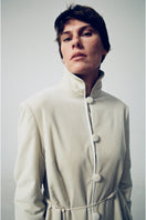Elegant ivory velvet coat by Delegan featuring a tailored fit and luxurious fabric, shown on a model in a fashion campaign photo.