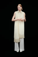 Warm ivory shirt scarf with silk fringe by DELEGAN, featuring soft fabric and elegant fringe detail in a stylish campaign setting.