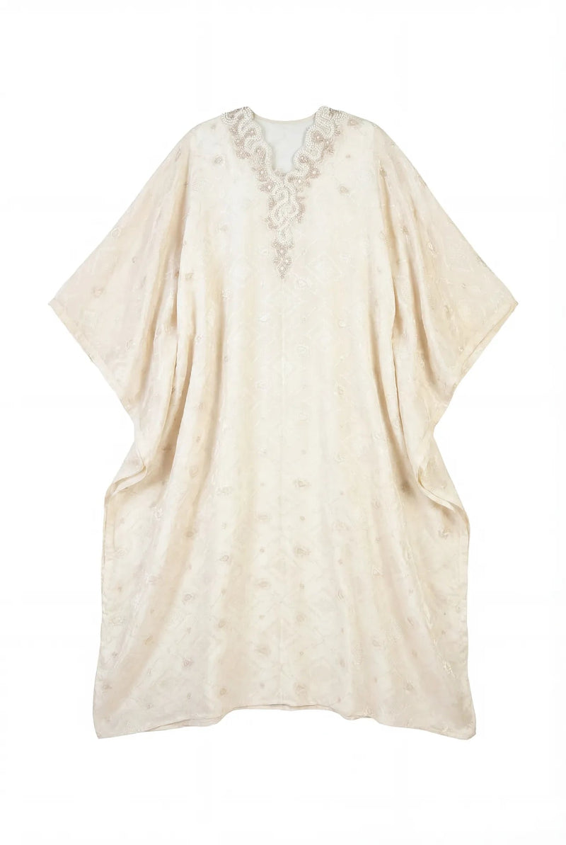Light gold embellished V-neck caftan maxi dress by Shatha Essa, featuring intricate embellishments and flowing fabric.