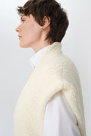 Close-up of a textured knit DELEGAN cardigan vest showing detailed stitching and soft fabric in natural light.