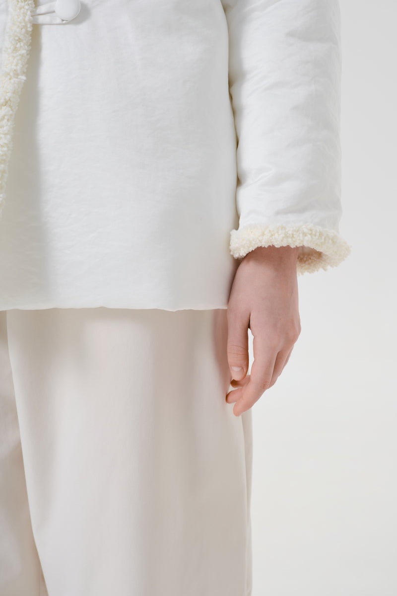 Close-up of a white Delegan jacket showing detailed stitching and fabric texture, highlighting the sleek design and craftsmanship.