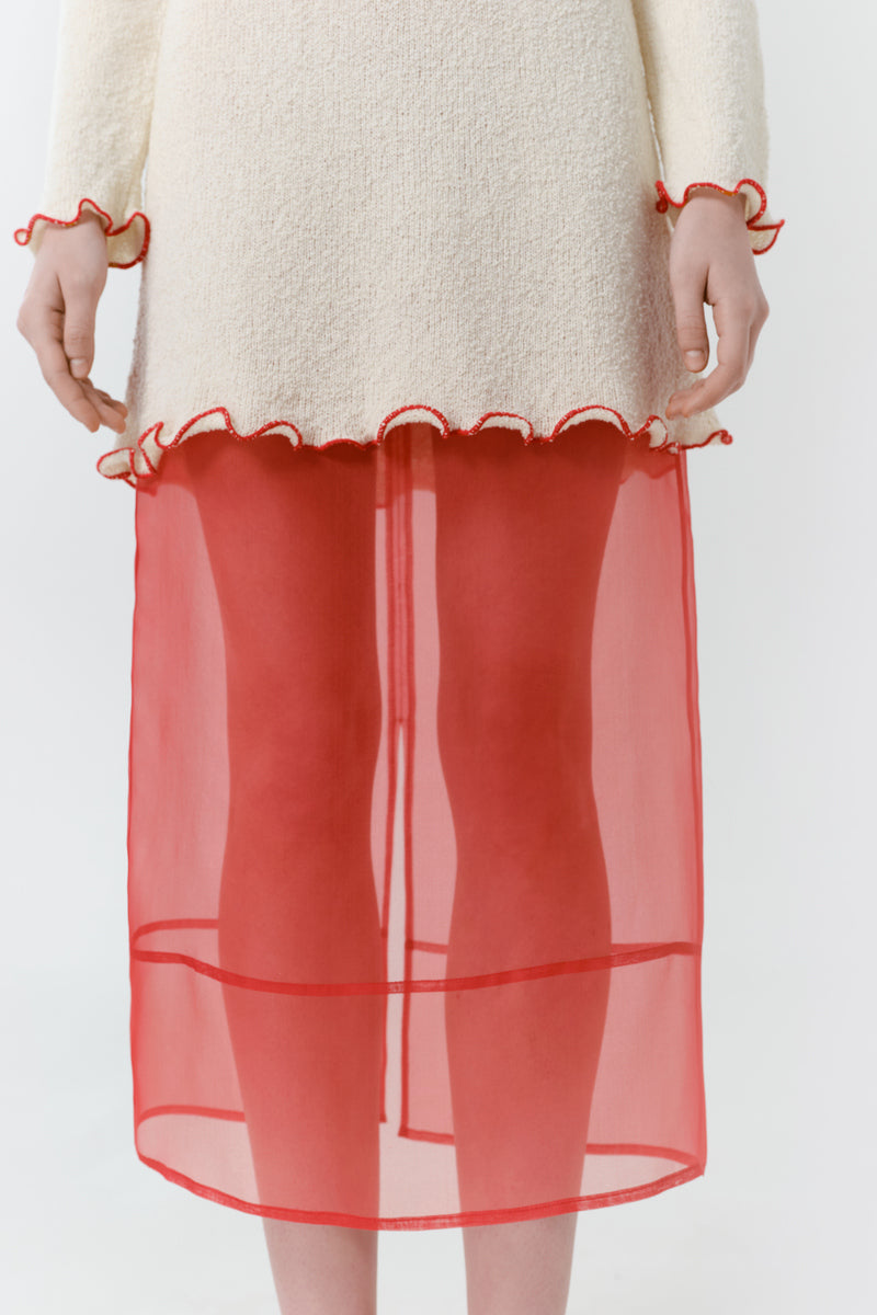 Red veil midi skirt by DELEGAN featuring flowing fabric and elegant design, shown in a close-up detail shot.