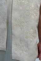 Close-up of a white milk embroidered vest by DELEGAN, featuring detailed floral embroidery and a sleek, fitted design.
