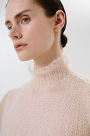 Close-up of a DELEGAN soft skin sheer knit top, showing the delicate fabric and fine texture of the women's top.