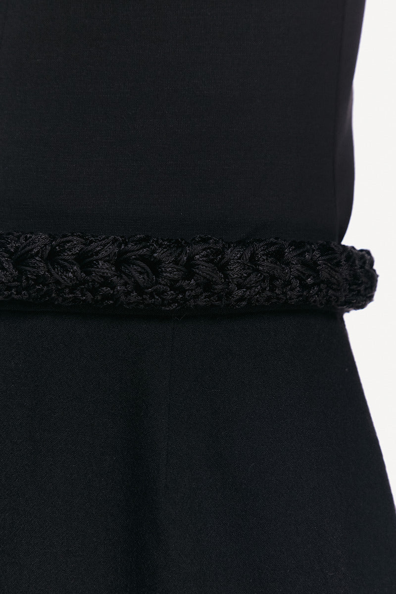 Close-up of a black midi skirt from DELEGAN, showing the fabric texture and detailed stitching for a stylish, modern look.