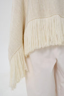 Close-up of DELEGAN Milk Blush Poncho cardigan, showing soft knit fabric and subtle pastel pink color.