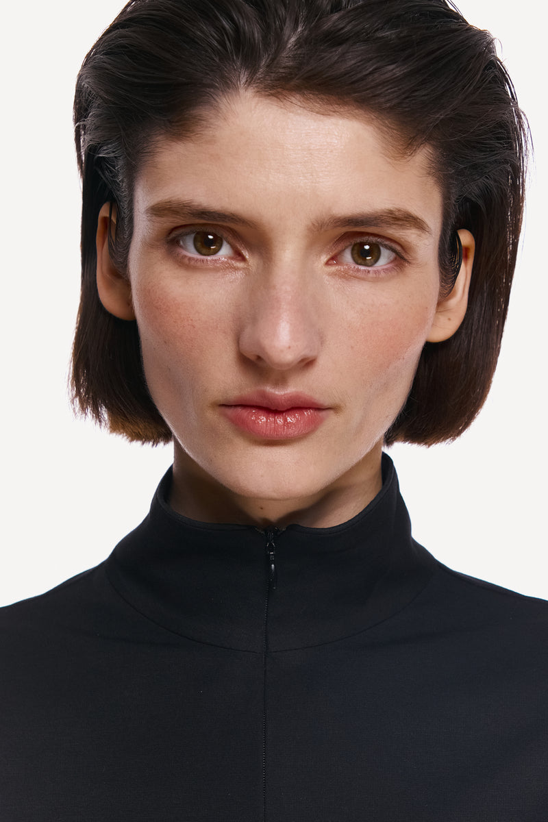 Close-up of a DELEGAN Coal Long Sleeve Top showing the fabric texture and detailed stitching.