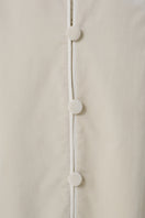 Close-up of a luxurious ivory velvet coat by DELEGAN, showcasing soft fabric and elegant stitching details.
