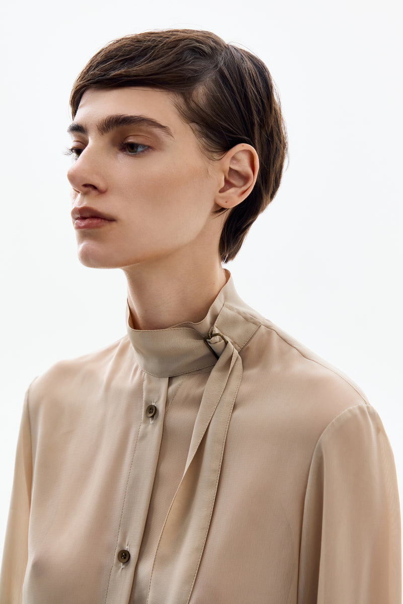 Close-up of a DELEGAN Nude Gold long sleeve blouse shirt with detailed fabric and elegant design.