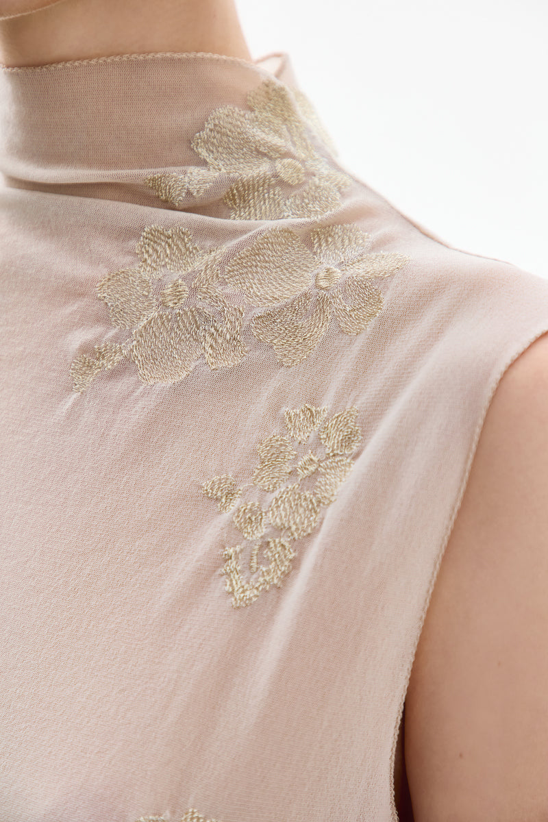 Close-up of a brass-colored bloom detail on DELEGAN's midi dress, showcasing elegant floral accents and fabric texture.