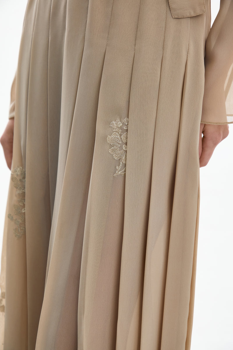 Close-up of a golden nude pleated midi skirt by DELEGAN, showing detailed fabric pleats and elegant texture.