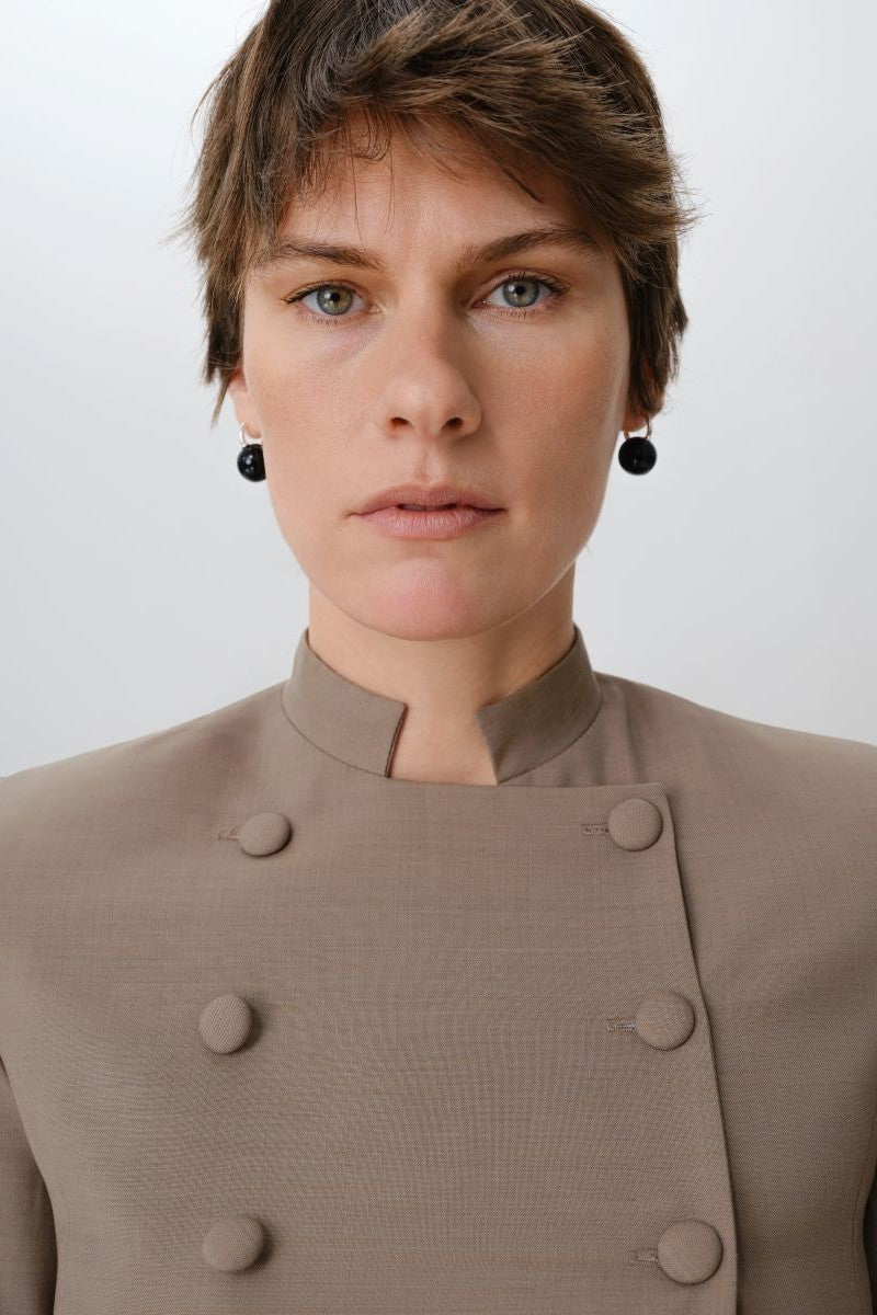 Close-up of a DELEGAN crop wool blazer showing textured wool fabric and tailored lapel detail.