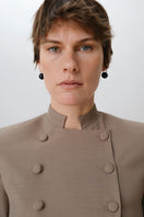 Close-up of a DELEGAN crop wool blazer showing textured wool fabric and tailored lapel detail.
