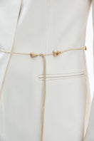 Close-up of a white and gold belted DELEGAN jacket showing fabric details and stylish belt design.