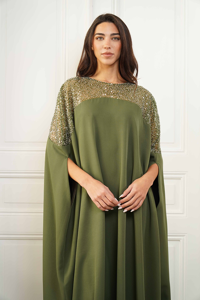Close-up of Joanna Andraos embroidered olive green gown showing detailed floral embroidery and luxurious fabric.