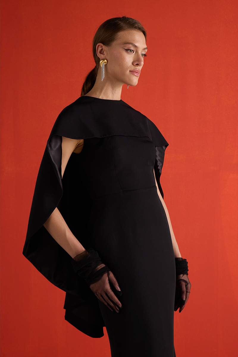 Close-up of Joanna Andraos black cascade gown showcasing flowing fabric and elegant draping details.
