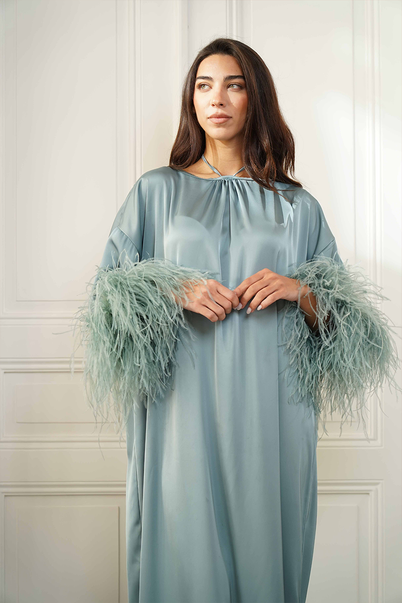Joanna Andraos silk gown featuring a tie-neck design with feather sleeves, close-up view highlighting luxurious fabric and elegant details.