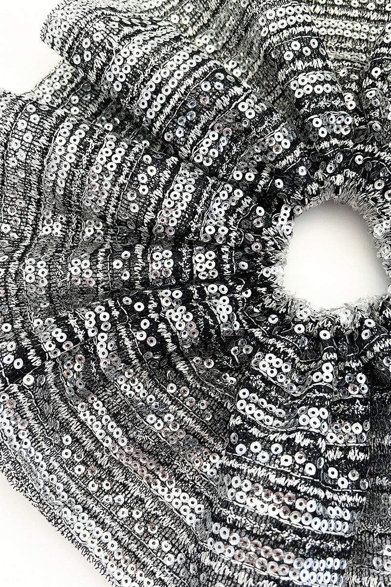 Aethera Branka X-Large Sequin Scrunchie in vibrant silver with shiny sequins, styled around a woman's hair.