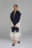 Navy Aethera Serene Lambswool Shawl draped over a chair, showcasing soft, cozy wool fabric and elegant design.