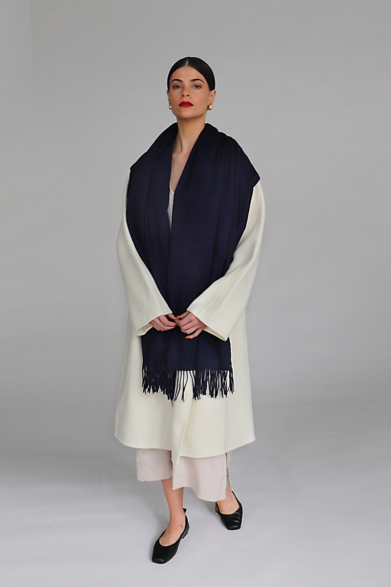 Navy Aethera Serene Lambswool Shawl draped over a chair, showcasing soft, cozy wool fabric and elegant design.