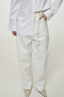 Light milk-colored relaxed fit jeans by DELEGAN, showing the denim fabric and casual style on a model.