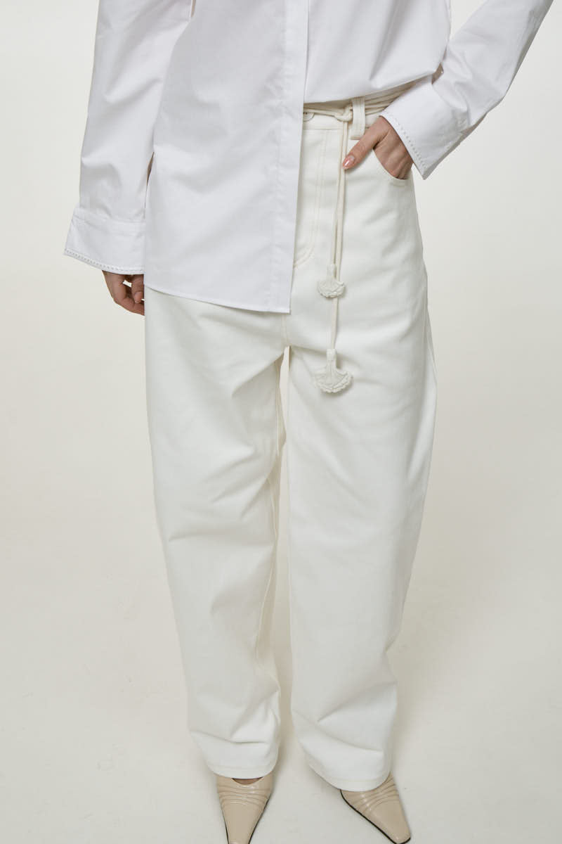 Light milk-colored relaxed fit jeans by DELEGAN, showing the denim fabric and casual style on a model.