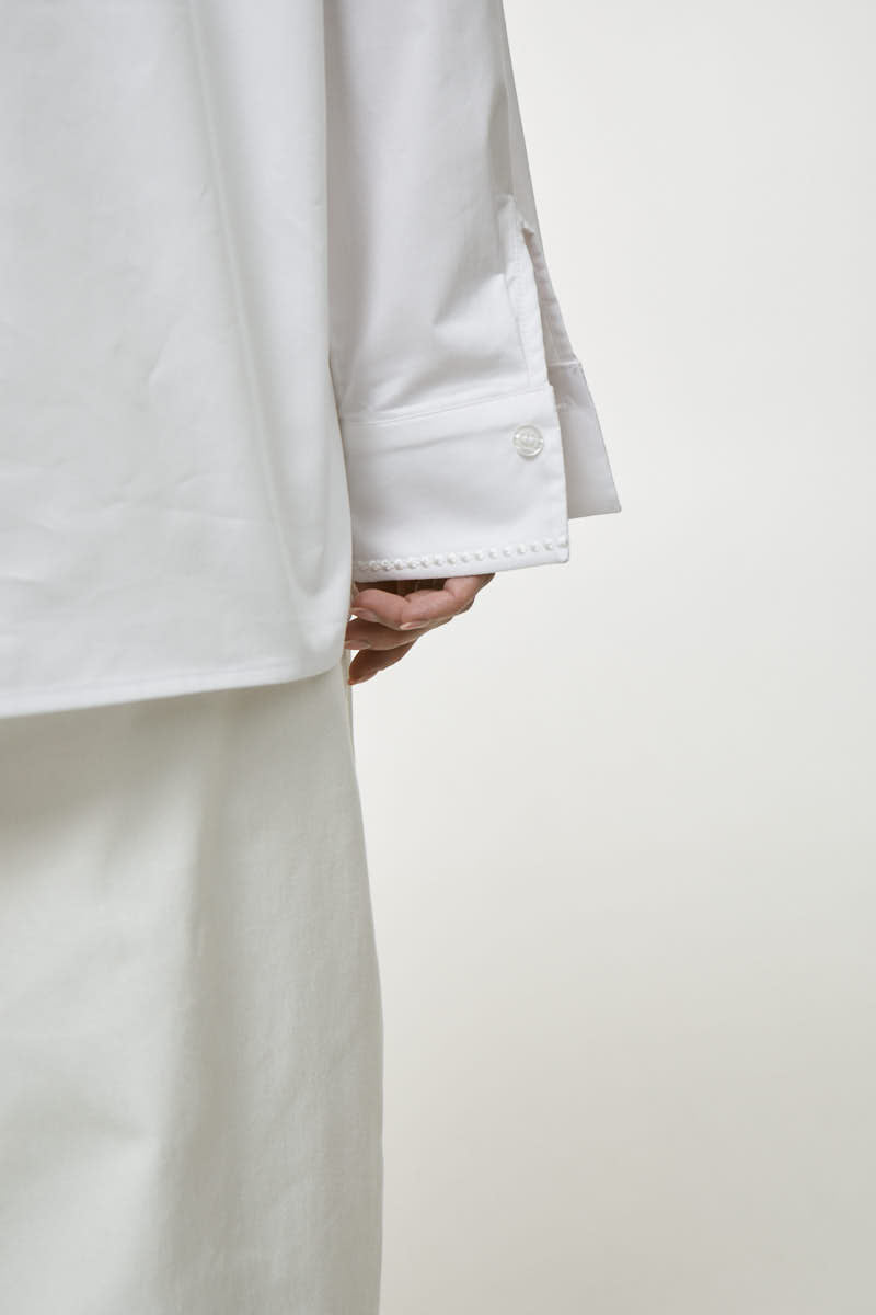 White embroidered shirt from DELEGAN, showcasing intricate embroidery and classic button-up design, perfect for casual or formal wear.