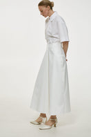 White cotton midi skirt by Delegan, featuring a flowing design and midi length, displayed on a neutral background.