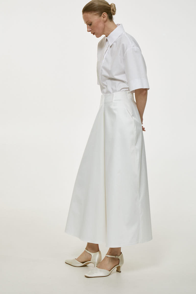 White cotton midi skirt by Delegan, featuring a flowing design and midi length, displayed on a neutral background.