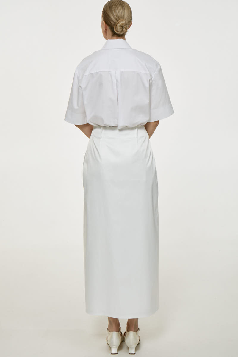 White cotton midi skirt by Delegan, showcasing the flowing fabric and high-waisted design, perfect for casual or dressy outfits.
