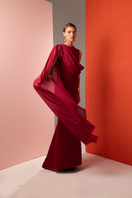 Joanna Andraos burgundy one-shoulder cape gown, front view showcasing elegant draped design and flowing fabric.