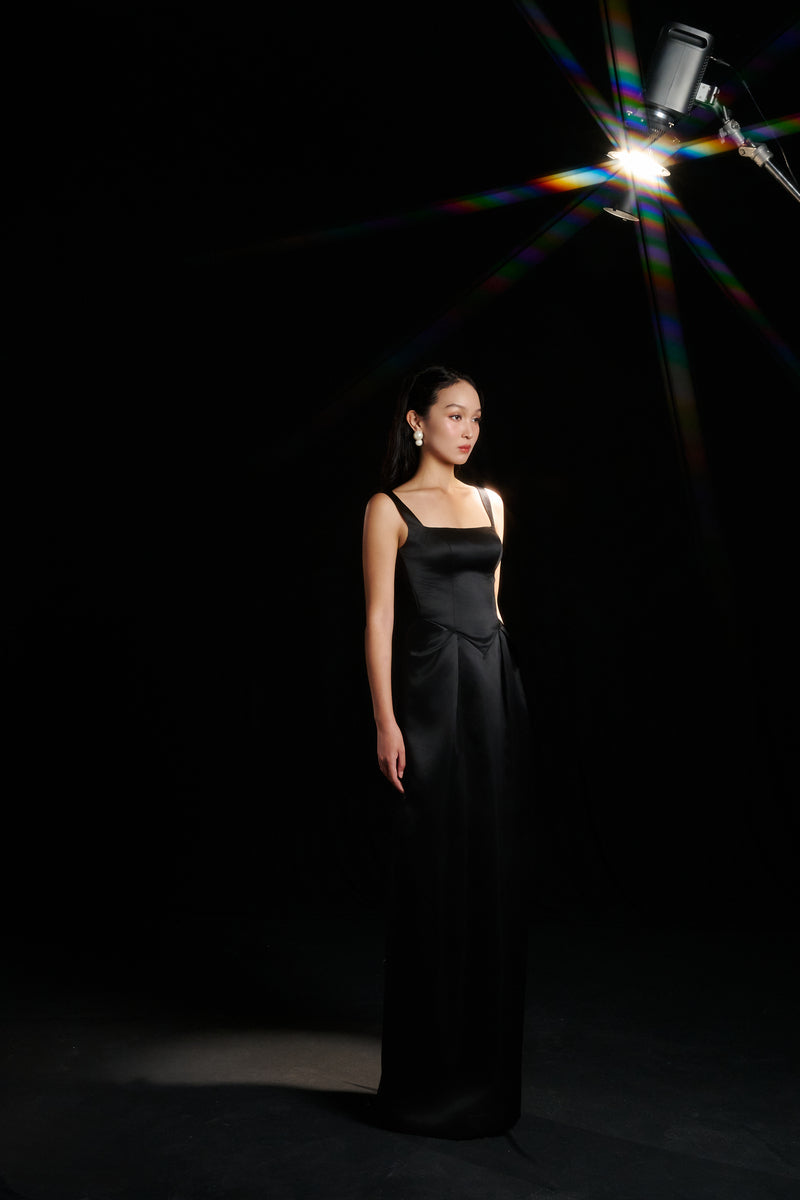 Black Amelia strap dress by HACCHIC COUTURE, elegant gown with fitted bodice and flowing skirt, showcased in a stylish fashion lookbook image.