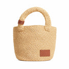 Beige raffia basket bag with top handle from Folklore The Label, featuring a woven texture and spacious design.