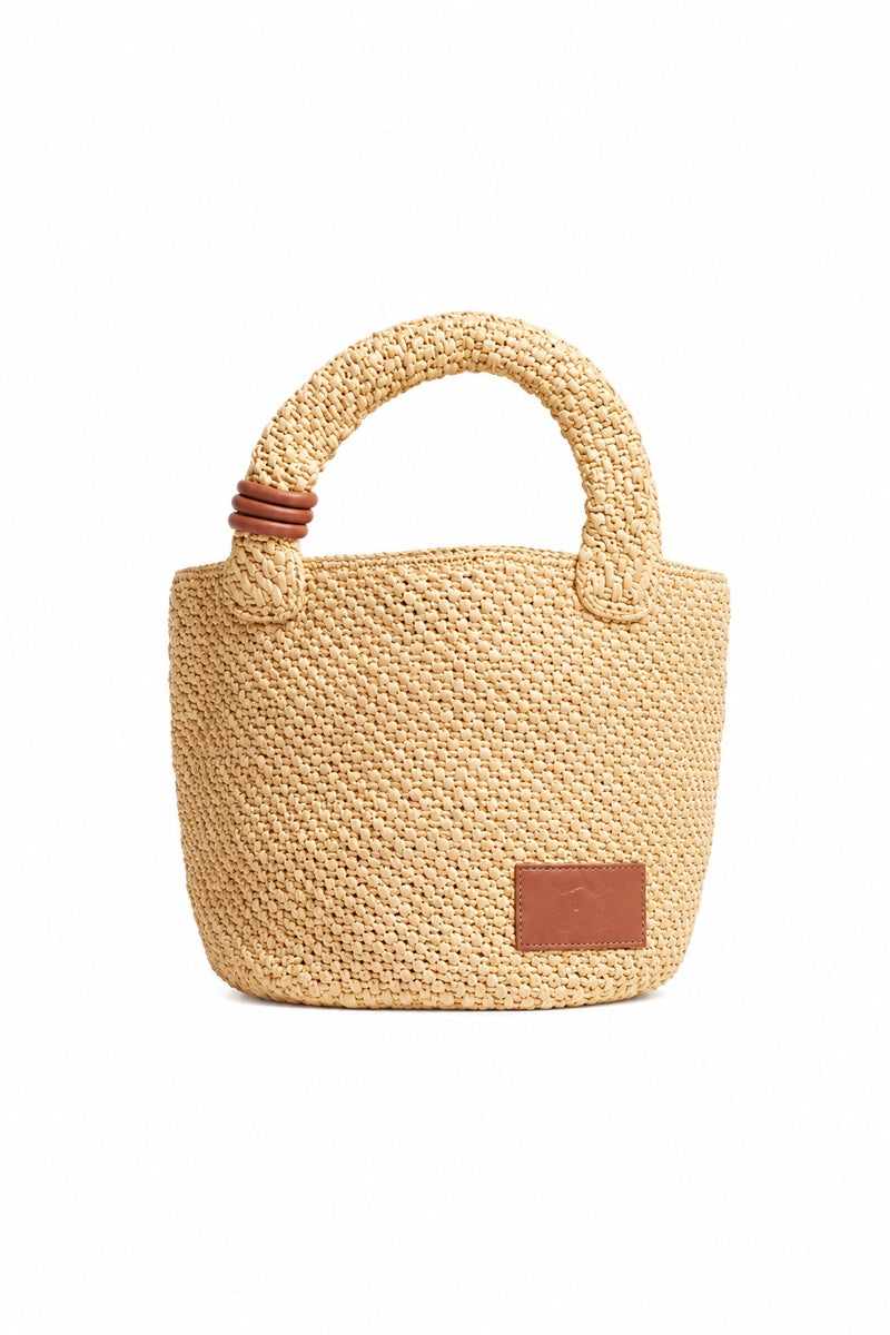 Beige raffia basket bag with top handle from Folklore The Label, featuring a woven texture and spacious design.