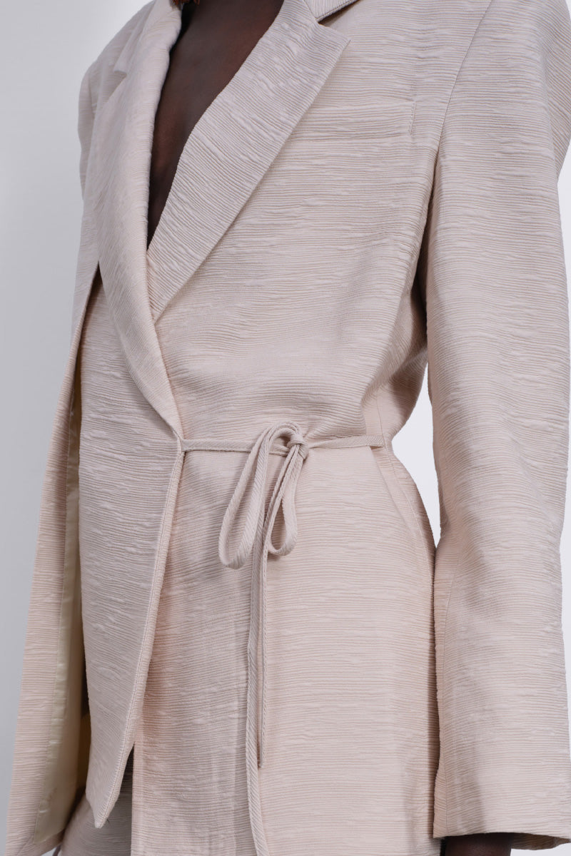 SÉLONE Helia wrap blazer in stone color, tailored blazer with a structured fit, featuring a wrap design and long sleeves.