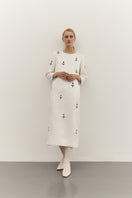 Elegant ivory midi dress with white ornament details by DELEGAN, shown on a mannequin in a high-resolution image.