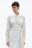 Pearl white wrapped blouse by Delegan, featuring elegant design, long sleeves, and a stylish fit, perfect for sophisticated casual wear.