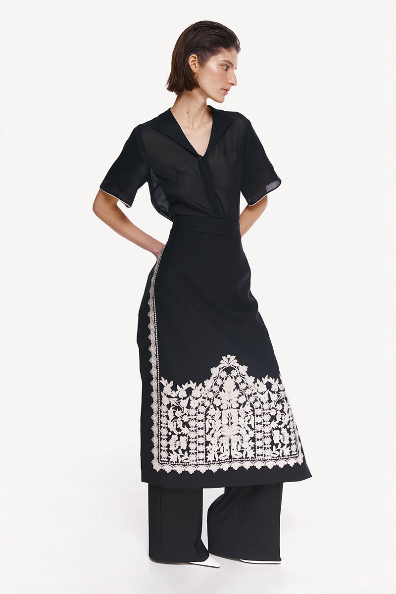 Elegant white filigree midi skirt by DELEGAN featuring intricate lace detailing and a flowy silhouette.
