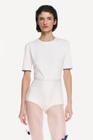 White short sleeve bodysuit by Delegan, close-up view showing fitted style and smooth fabric, ideal for casual and layered outfits.