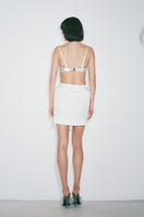 White Nué Margot mini skirt displayed on a hanger, showcasing its stylish design and clean silhouette.