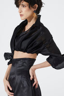 Black BABUKHADIA Aline maxi skirt with flowing fabric and high waist, displayed on a hanger against a neutral background.