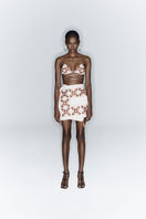 White maxi skirt by JC Pajares with hand embroidery in brown and orange, featuring a cross design and flowing fabric.