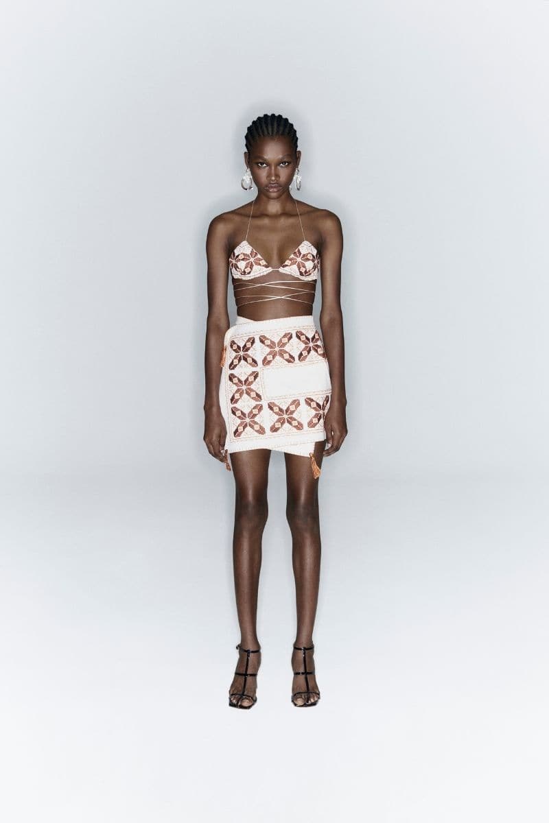 White maxi skirt by JC Pajares with hand embroidery in brown and orange, featuring a cross design and flowing fabric.