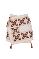 White maxi skirt by JC Pajares with hand embroidery in brown and orange, featuring a cross design and flowing fabric.