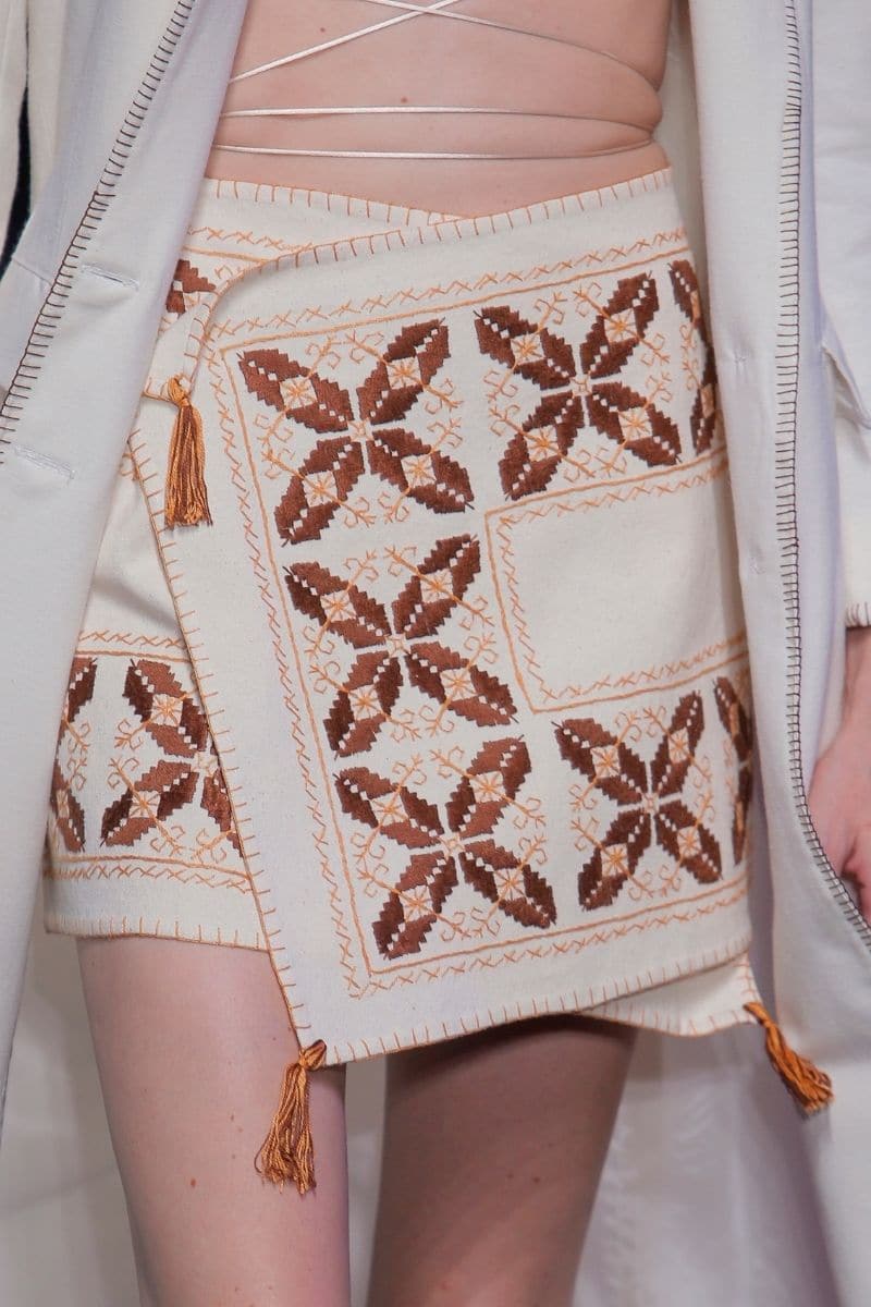 White maxi skirt by JC Pajares with hand embroidery in brown and orange, featuring a cross skirt design.