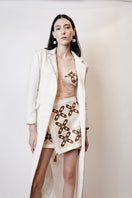 White maxi skirt by JC Pajares with hand embroidery in brown and orange, featuring a cross design and flowing fabric.