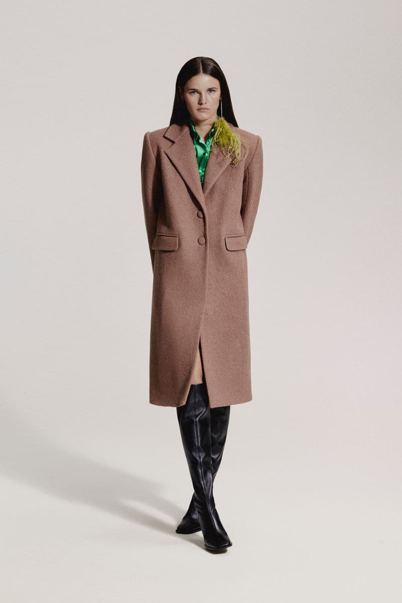 JC Pajares curly camel wool coat displayed on a hanger, showcasing its textured fabric and classic style.