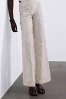 SÉLONE Jora fringe trousers in cream, stylish pants with fringe details, shown in a relaxed fit on a model.