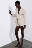 White JORA fringe shorts by SÉLONE featuring layered fringe detailing and a relaxed fit, shown on a model.