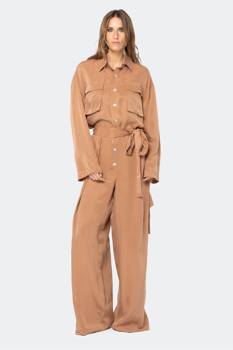 niLuu Serengeti Mocha jumpsuit featuring a sleeveless design and waist tie, displayed on a model with a neutral background.
